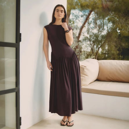 A model wears an Albaray Dipped Drop Waist maxidress with flip-flops with an outdoor balcony and trees in the background