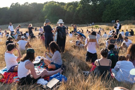 People gather on dry grass on Hampstead Heath to watch the eclipse