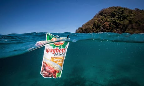 An empty sachet of 'spaghetto sauce' floating in a blue sea off a tropical island