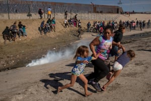 Maria Meza, a migrant woman from Honduras, part of a caravan of thousands from Central America trying to reach the United States, runs away from tear gas with her five-year-old twin daughters in front of the border wall between the US and Mexico, in Tijuana, Mexico 25 November 2018