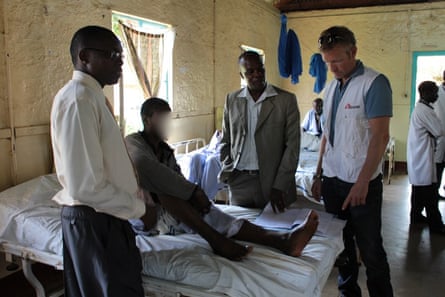 Methanol patent lying on bed with others gathered around