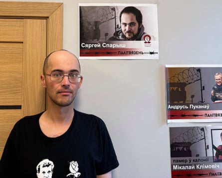 Former political prisoner Sergei Sparysh stands beside a poster showing him before his imprisonment