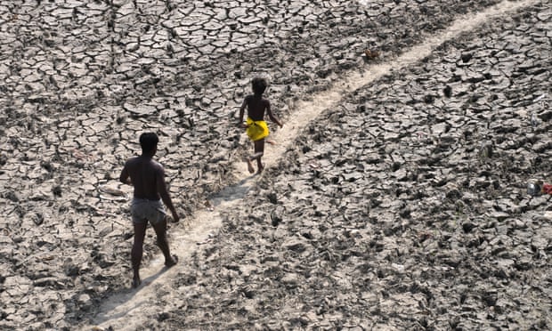 A man and a boy walking across a dry, cracked riverbed