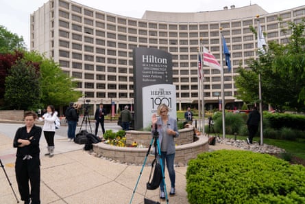 reporters stand outside hotel building with cameras set up