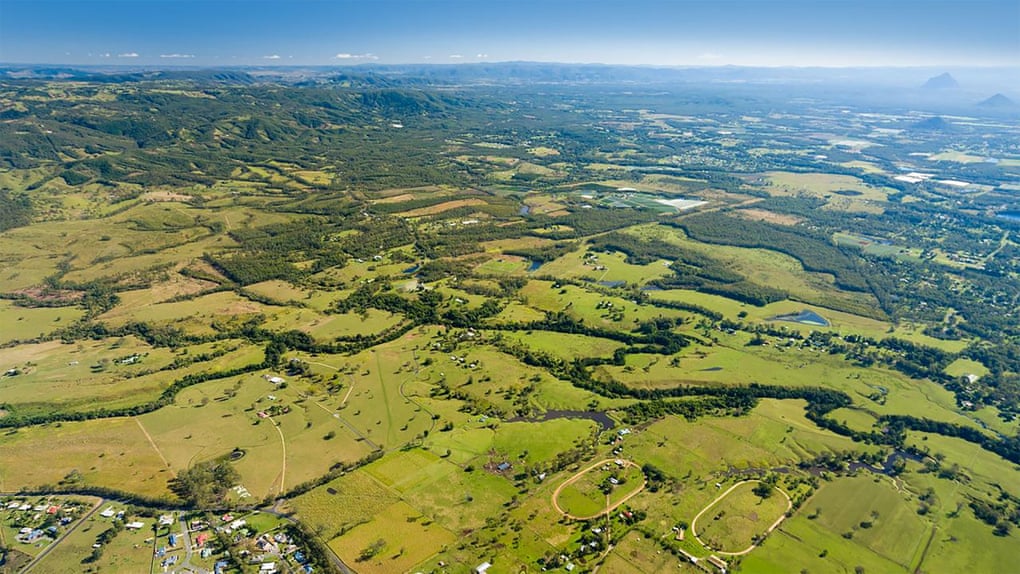 Aerial view of rural Queensland showing green hills, paddocks, trees and houses
