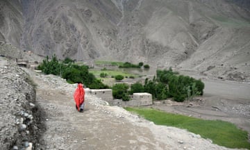 An Afghan girl walking towards a flooded village in the mountains of Afghanistan