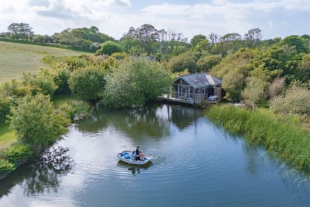Cabin next to a large pond with a person on a boat in it