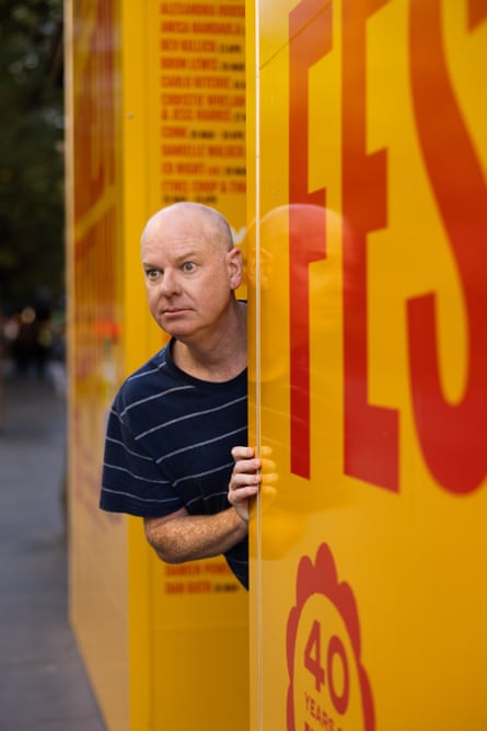 Gleeson peeks out a doorway emblazoned with comedy festival signage