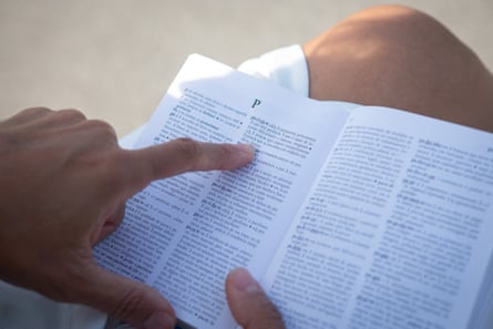 A woman’s finger is tracing text in a Portuguese dictionary