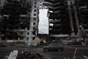 A car rides in front of a destroyed apartment building in Borodianka, Ukraine.