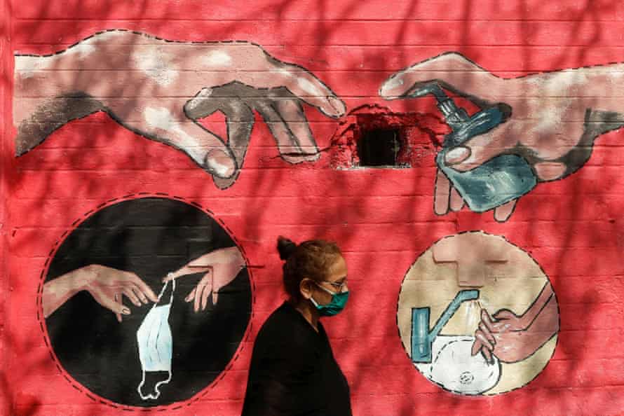 A woman walks past a street art illustrating measures to protect from the spread of Covid in Mumbai, India.