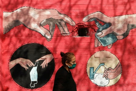A woman walks past a street art illustrating measures to protect from the spread of Covid in Mumbai, India.