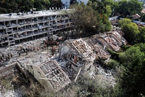 An overhead view of emergency services personnel working at a badly damaged residential site, with roofs and windows torn off