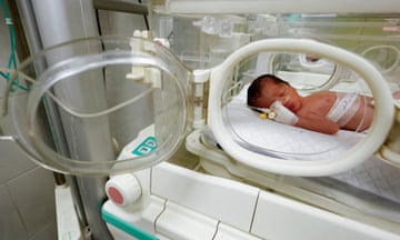 A newborn baby lying in an incubator in a hospital