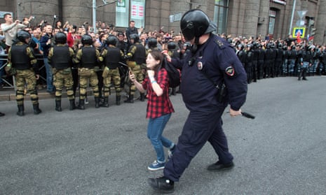 A Russian police officer detains a teenager during rally in St Petersburg protesting against retirement age increases.