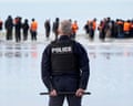 A policeman watches on as people attempt to board a small boat in Gravelines, France