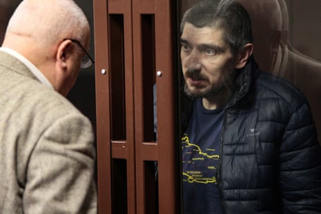 Anton Cherednik, a Ukrainian serviceman captured in Mariupol and accused of killing a civilian in March 2022, sits in the defendant’s cage and speaks with his lawyer during a hearing in the Southern District military court in Rostov-on-Don, Russia.