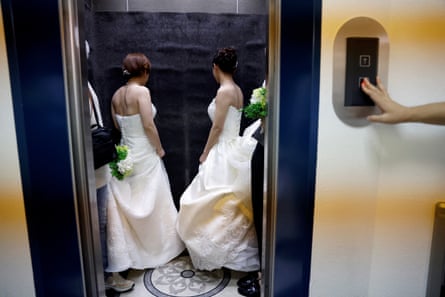 Two women in white wedding dresses in a lift