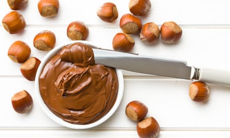 Chocolate hazelnut spread in a bowl surrounded by hazelnuts