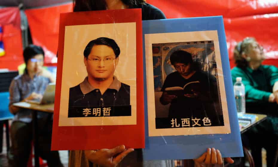 A volunteer holds placards of detained Taiwanese activist Lee Ming-cheh and Tibetan education advocate Tashi Wangchuk.