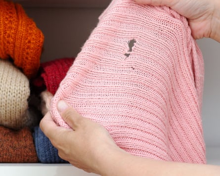 Woman hands holding a knitted cloth with a hole made by a moth