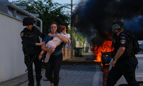 Police officers evacuate a woman and a child from a site hit by a rocket fired from the Gaza Strip in Ashkelon, southern Israel on 7 October.