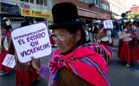 An Indigenous woman marching in a protest in a bowler hat and traditional multicoloured shawl