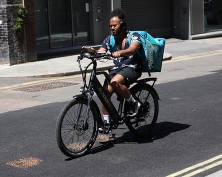 An Uber food delivery rider cycles a bike as they work in the sun during a heatwave, in central London.
