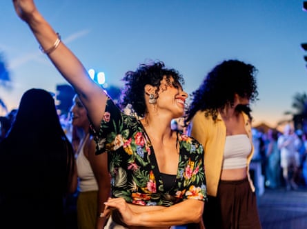 Happy mature woman dancing with friends at a music festival.