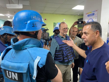 A hospital surgeon talks to a man in a blue UN-branded vest and helmet