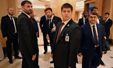 Adam Kadyrov among a group of besuited officials in the lobby of a hotel