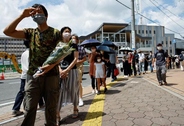 People queue up to offer flowers and pray at the site where Shinzo Abe was shot