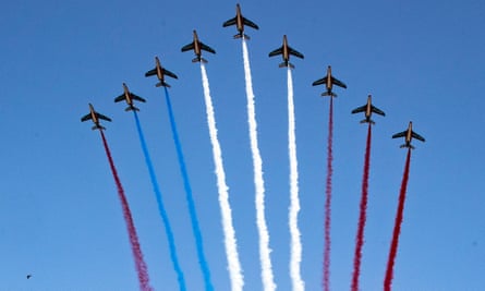 Nine planes in the sky, with coloured trails behind them: one of the red trails should be blue