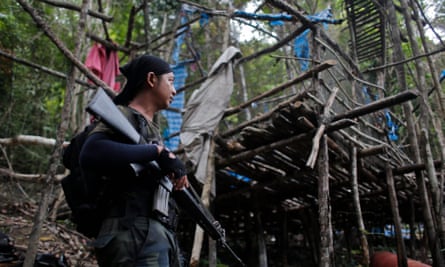 An armed Royal Malaysia Police stands guard in an abandoned camp in which graves are found at Wang Burma hills at Wang Kelian, in Malaysia.
