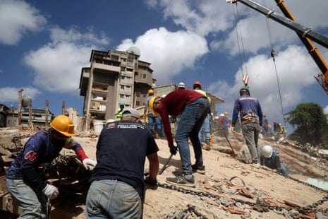 Workers set up a chain for crane to remove a large piece of debris as part of the search and rescue efforts at the collapsed residential building Rita in the San Bernardino neighborhood after a magnitude 7.2 earthquake struck Venezuela.