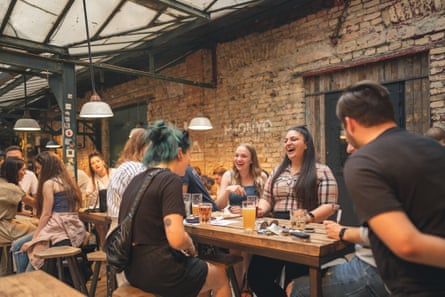 Bar with brick, big tables and people laughing
