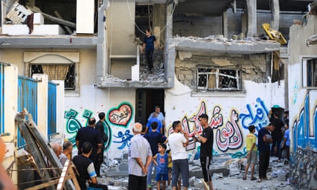 A group of Palestinian men and young children standing amid the ruins of bombed-out building