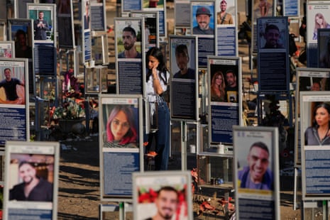 A woman stands at a memorial site displaying images of the victims.