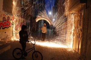 Gaza, Palestine. A youth swings a homemade firework sparkler, as people celebrate before the month of Ramadan