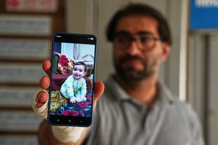 Fahd holding up a smartphone with a photo of Sam on it