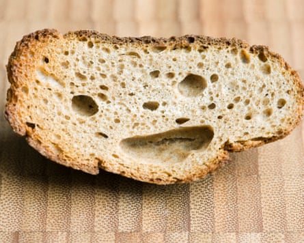 Piece of whole wheat bread with holes appearing like a smiley face