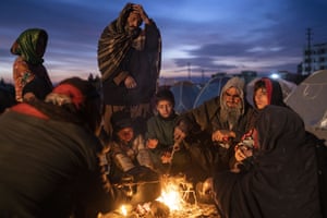 A family warm up next to a makeshift fire outside the Directorate of Disaster office where they are camped in Herat.