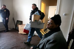 An evicted woman watches as a removal company moves her property out of her rented apartment on to the pavement.
