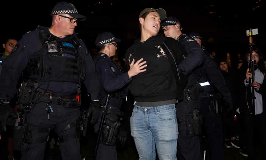 Police detain a man during a rally at the State Library in Melbourne
