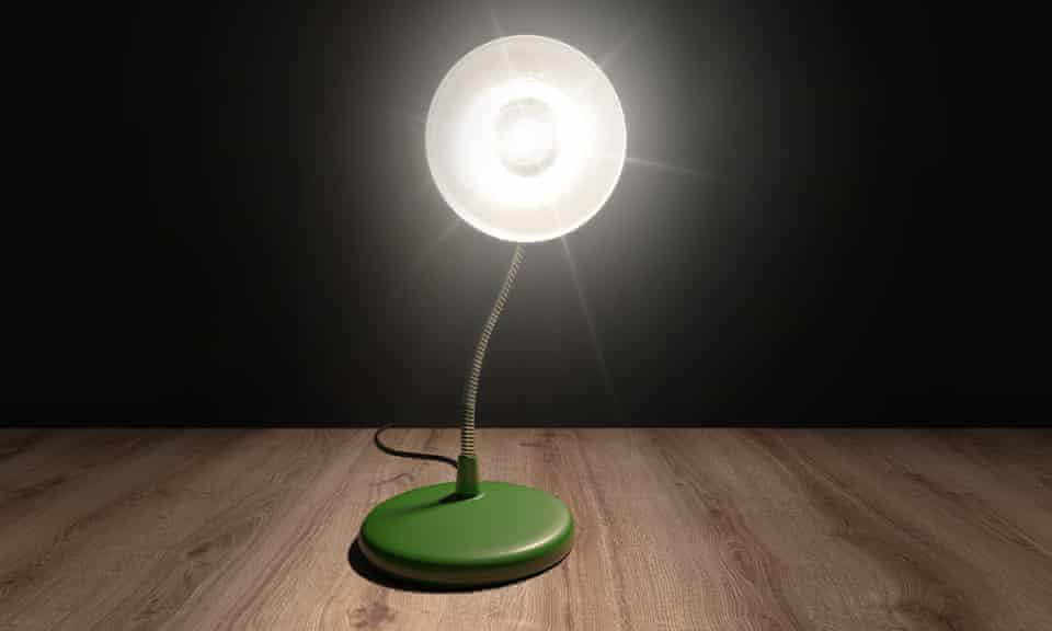 A desktop lamp in a dark room pointing brightly at the viewer. 