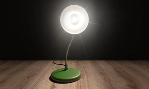 A desktop lamp in a dark room pointing brightly at the viewer. 