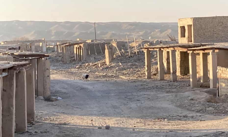 battered buildings and rubble line a road