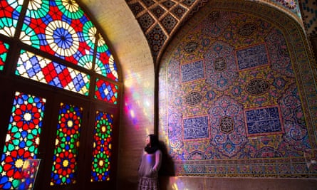 A young women rests next to a glowing stain-glassed window in Shiraz, Iran.