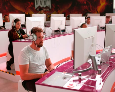 A group of people sitting in front of screens, wearing headphones, playing a video game
