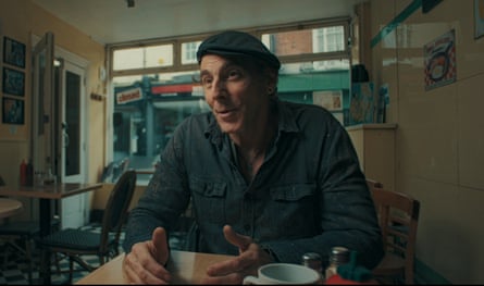 Marcus read sits in a cafe wearing a beret and a dark shirt.